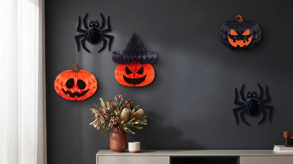 Premium honeycomb paper pumpkins and spider ornaments displayed on a charcoal wall in a modern, well-lit interior.